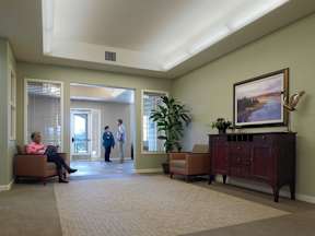A man and a woman are talking in a hallway with a painting on the wall.
