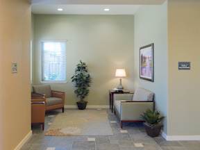 A hallway with a rug and two chairs.