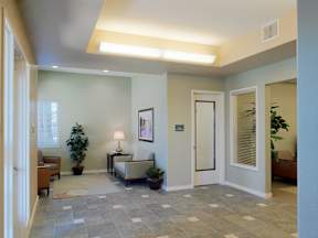 A hallway with a bench, lamp, and potted plant.