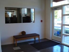 A room with a bench and a mirror on the wall.