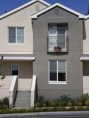 A grey two story house with a balcony on the second floor.