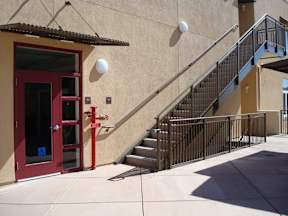 A red door with a glass window is on the left side of a staircase.