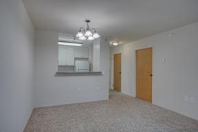 A spacious room with a kitchen area and a chandelier.