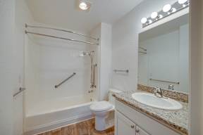 A white bathroom with a toilet, sink, and a shower with a glass door.