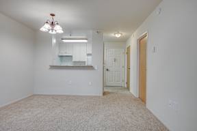A room with a carpeted floor and a chandelier hanging from the ceiling.
