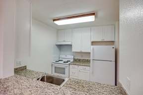 A kitchen with white cabinets and appliances.