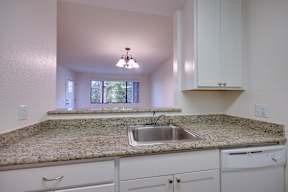 A kitchen with granite countertops and white cabinets.
