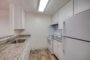 A kitchen with granite countertops and white appliances.