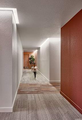 A person is walking down a hallway with a Christmas tree at the end.