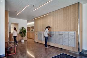 A woman is standing in front of a row of mailboxes.