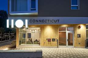 The front of a hotel called Connecticut with a lit up sign.