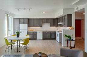 A modern kitchen with a white refrigerator and yellow chairs.