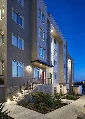 A modern apartment building with a well-lit entrance and landscaping.