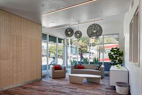 A waiting area with a couch, chair, and decorative hanging lamps.