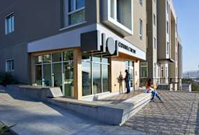 A modern building with a glass entrance and people standing outside.