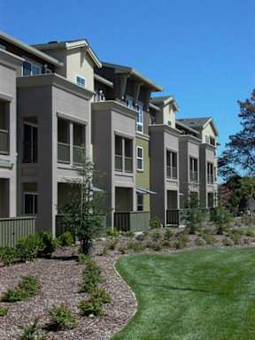 A row of modern apartment buildings with green lawns in front.