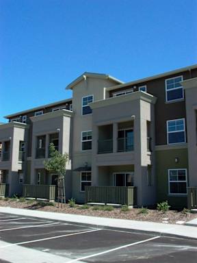 Apartment building with a parking lot in front.