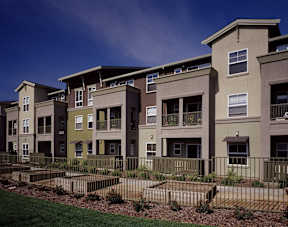 A row of modern apartment buildings with green lawns in front.