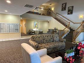 A living room with a couch, chairs, and a staircase.