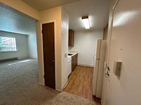 A kitchen area with a refrigerator, sink, and cabinets.