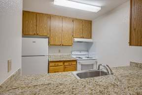 A kitchen with granite countertops and wooden cabinets.