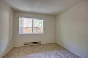 A room with a window and a vent on the wall.