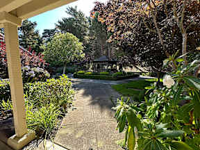 A gazebo is surrounded by trees and plants in a garden.
