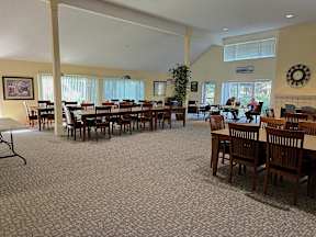 A large room with tables and chairs and a clock on the wall.