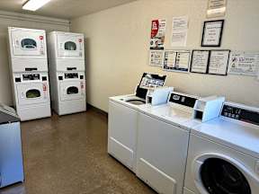 A laundromat with washers and dryers and a wall of notices.
