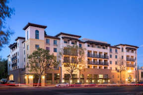 A large, modern apartment building with multiple balconies and lights on.