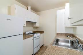 A kitchen with a white fridge, stove, and sink.at Terra Linda Manor, San Rafael California