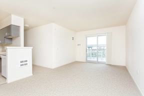 A white kitchen with a refrigerator, cabinets, and a window.