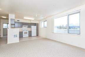 A spacious kitchen with white appliances and a large window.