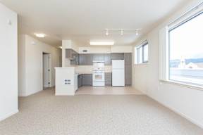 A clean, empty room with a kitchenette and a window overlooking a cityscape.