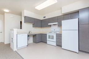 A kitchen with white appliances and grey cabinets.