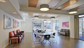 A room with a long couch, chairs, and a table.