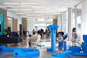 A group of children playing with blue blocks in a brightly lit room.