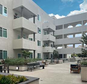 A courtyard with benches and plants in front of a concrete building.