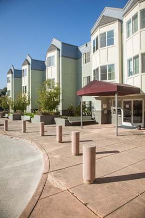 A building with a red awning is surrounded by concrete bollards.