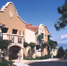 A woman is walking in front of a building with a clock on it.