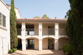 A white building with a red tile roof and a balcony.