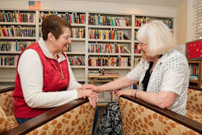 Two women holding hands in a library.