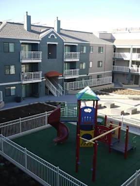 A playground with a red slide and a green roofed structure.