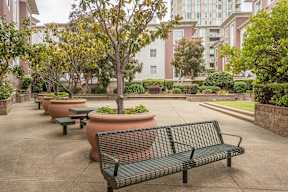 A park with benches and trees in front of a building.