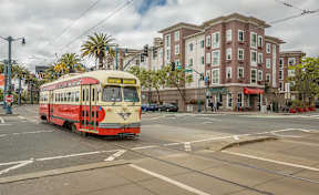 A red and white tram is on a city street.