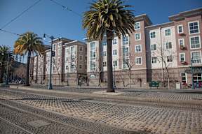 A street with a tram track in the foreground and a building in the background.
