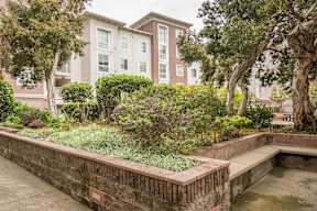 A brick wall with a small pond in front of a building.