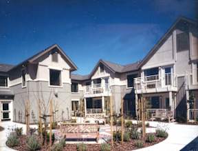 A large house with a balcony and a small garden in front.