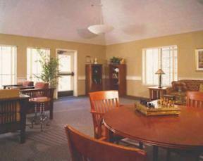 A room with a wooden table and chairs, a bookcase, and a chessboard.