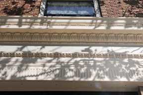 A building with a window and a wall with carved text.